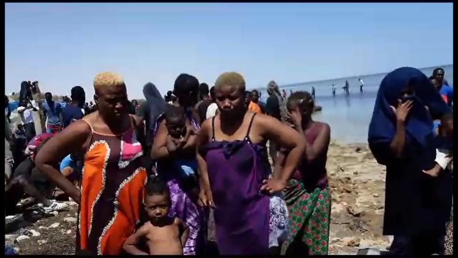  نساء وأطفال طردتهم السلطات الليبية إلى الحدود الليبية يقفون شاطئ البحر، 6 يوليو/تموز 2023. 