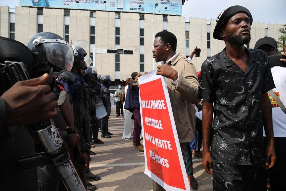 Protester holds sign in front of a line of riot police