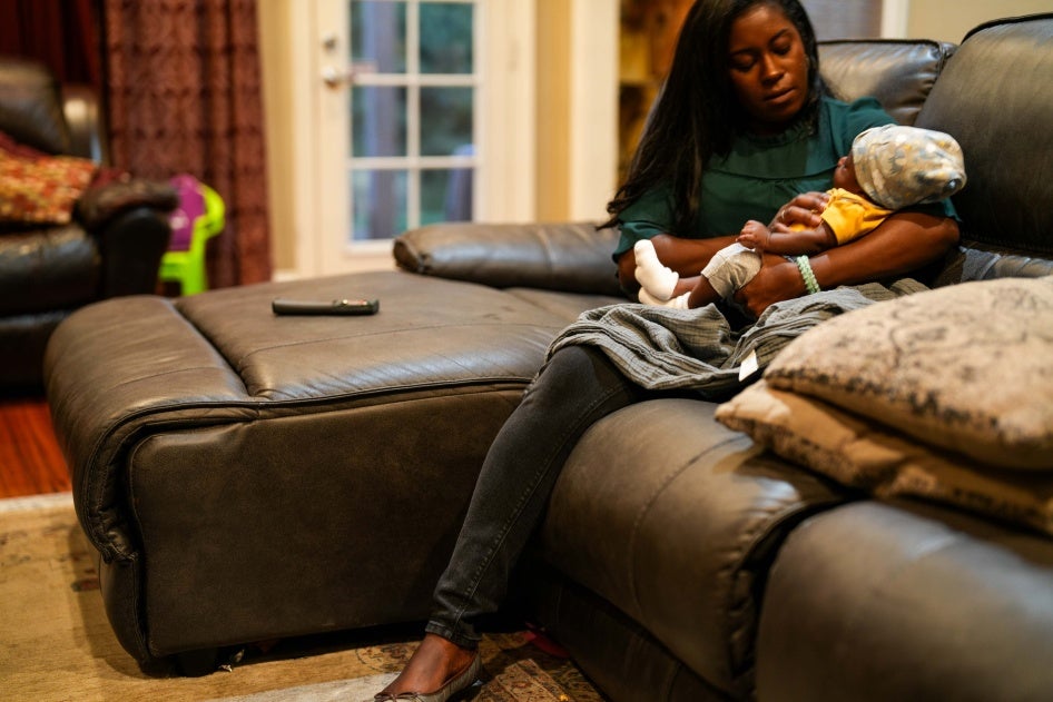 A woman holds a baby on a couch