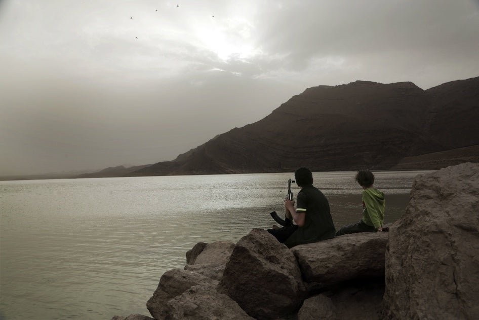 A boy, believed to be recruited by the Houthis, holds an AK-47 while overlooking the high dam in Marib, Yemen, July 30, 2018.