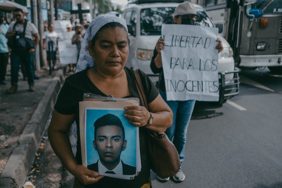 A woman holds a photo of her son at a protest