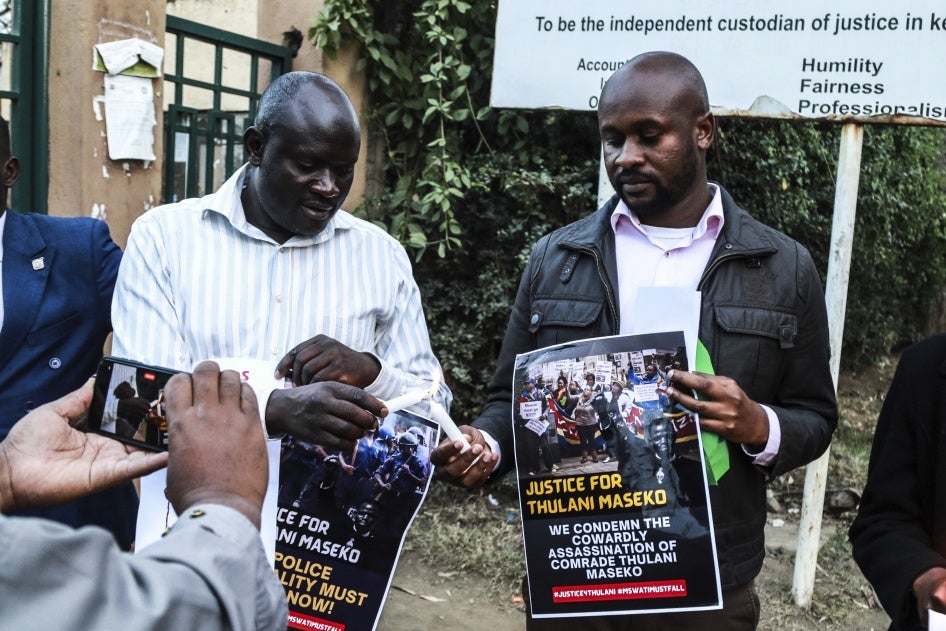 Activists light candles while holding posters at a tribute to the assassinated human rights lawyer Thulani Maseko, Eswatini, formerly Swaziland