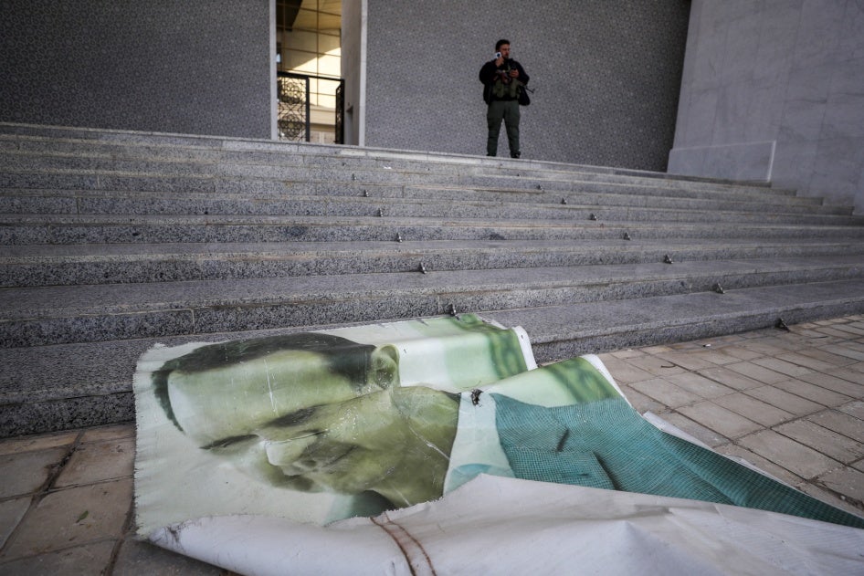 A picture of former Syrian President Bashar Assad lies on the ground as a Syrian opposition fighter stands nearby, inside the Presidential Palace in Damascus, December 8, 2024.