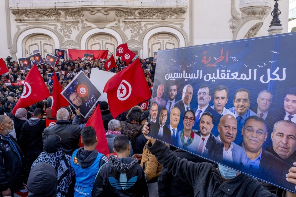 Protesters hold up placards and Tunisian flags