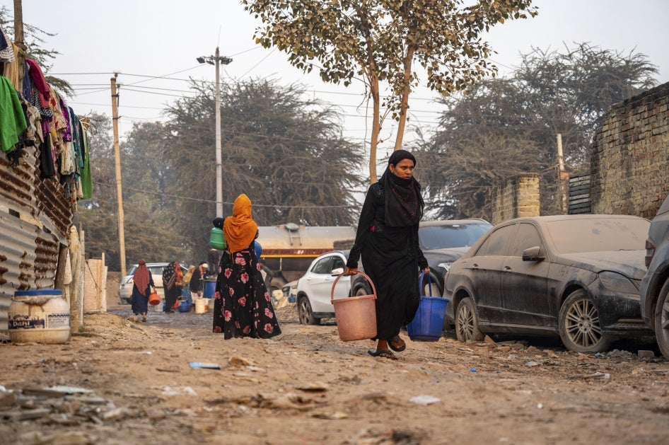 A Rohingya woman carries drinking water in Madanpur Khadar refugee camp, India, January 14, 2024.