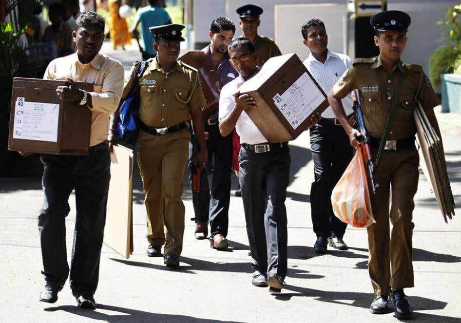 Polling officers carrying ballot boxes walk with a police officer as they prepare to go to their polling centers ahead of presidential election in Colombo on January 7, 2015.