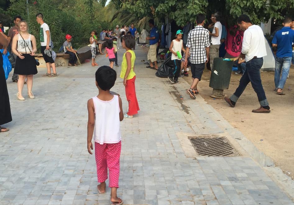 Children from Afghanistan play with a local volunteer at a makeshift camp in Pedion tou Areos. Earlier this week, the government announced a plan to move people from the park to an open camp it plans to create. 