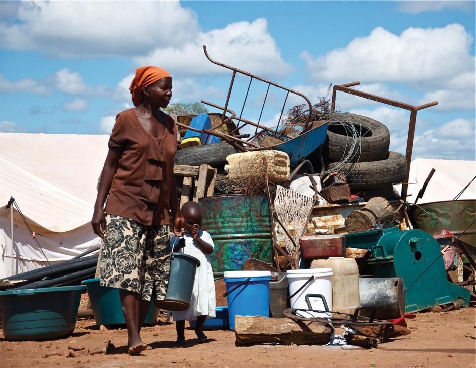  A woman stands in front of a pile of her household property at Chingwizi transit camp, which the government forcibly shut down in August 2014. Hundreds of families lost their property left in the open during their relocation to the camp. March 2014.