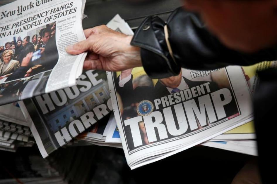 A man hands a newspaper to a customer at a news stand in New York, U.S., November 9, 2016.