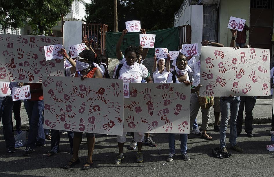 Manifestation d’activistes devant la chapelle de l'école Saint-Louis de Gonzague à Port-au-Prince le 11 octobre 2014, lors des funérailles de Jean-Claude «Baby Doc» Duvalier, afin de rappeler les nombreuses violations des droits humains dont s’était rendu