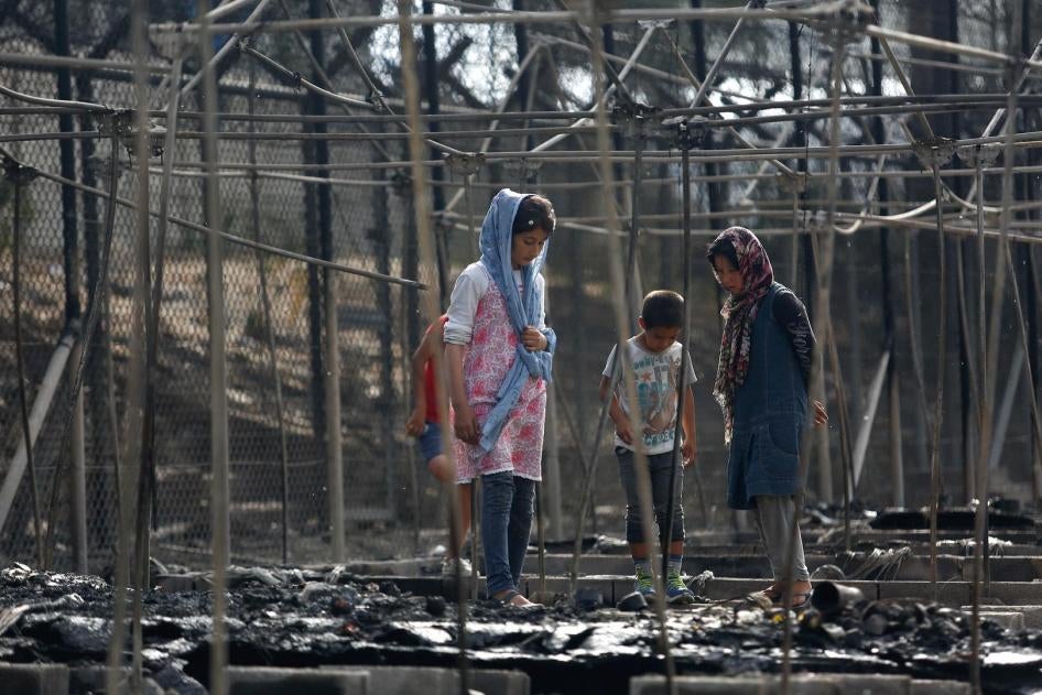 Asylum seekers stand among the remains of a burned tent at the Moria migrant camp, after a fire started in the camp ripped through tents and destroyed containers, on the island of Lesbos, Greece, September 20, 2016.