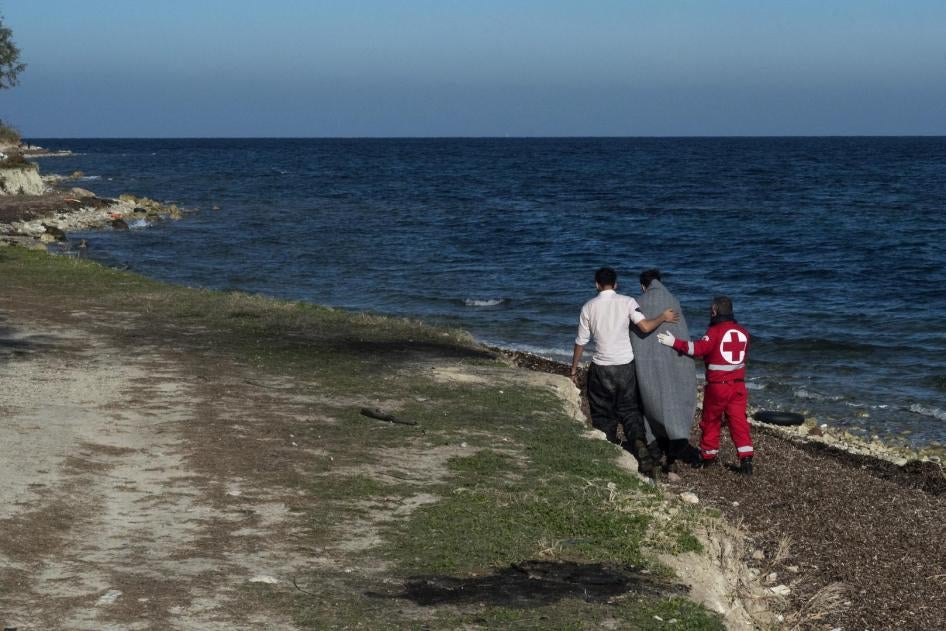 Member of Greek Red Cross helps an Afghan refugee who has just arrived from Turkey with an inflatable boat in the area of airport of Mytilene, Lesvos Island, Greece.