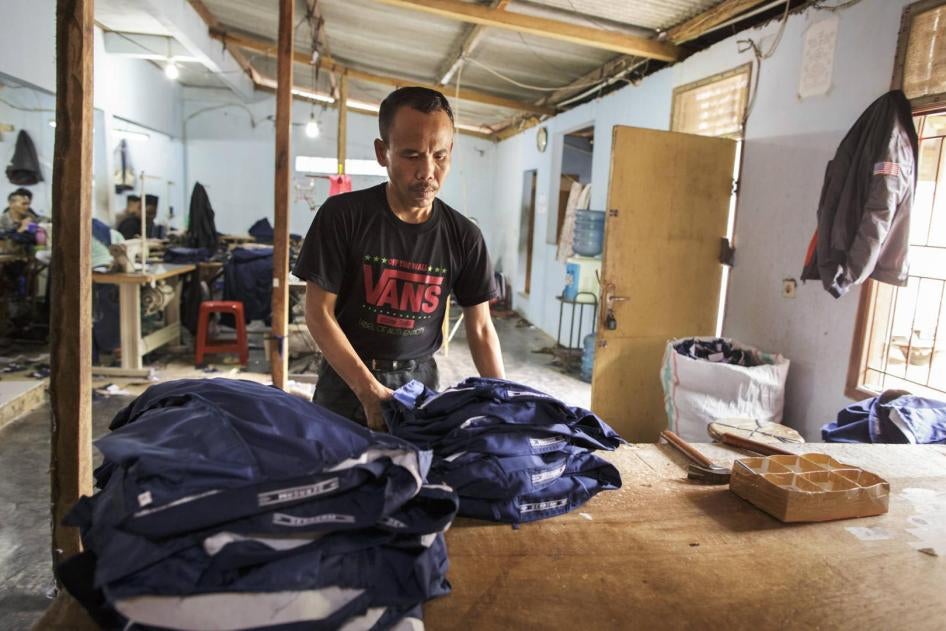 Man working in a clothing factory in Indonesia, stitching buttons 