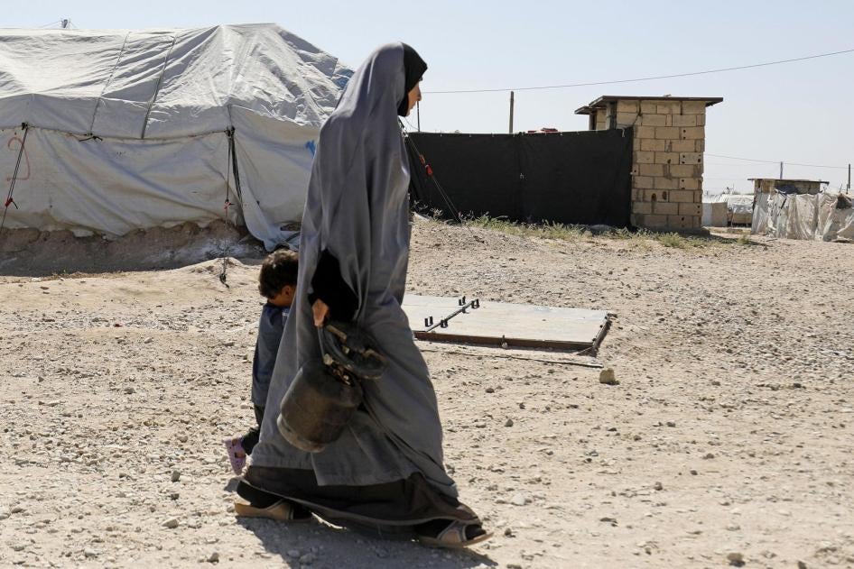 A woman walks with a child in Roj camp, which holds foreign wives and children of Islamic State (ISIS) members, in northeast Syria, September 2018. © 2018 Delil Souleiman/AFP/Getty Images