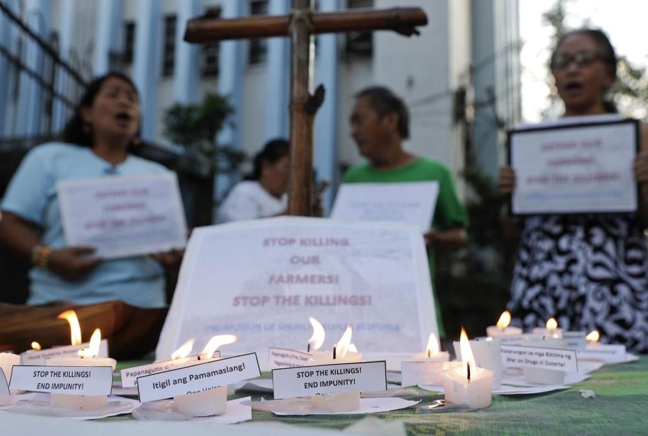 Activists shout slogans and offer prayers Monday, April 1, 2019, to protest the killings of what they claim were farmers in a central Philippine province. 