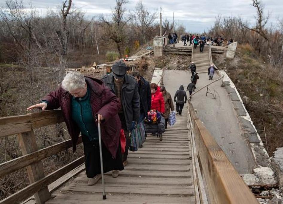 Older people crossing the broken bridge at the Stanytsia Luhanska checkpoint.