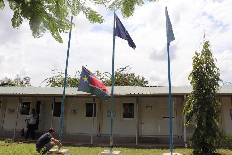 A man raises a flag outside the IOM compound in South Sudan
