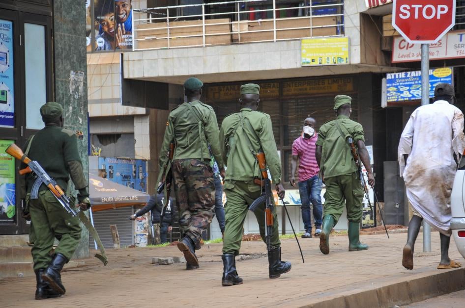 Des policiers et des membres des forces de sécurité patrouillent dans une rue de Kampala, en Ouganda, le 26 mars 2020, afin de veiller à la stricte application de mesures décrétées pour endiguer la propagation du coronavirus. 