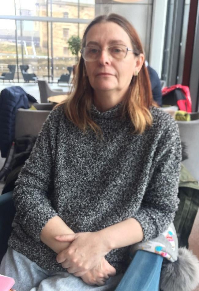 A woman in a gray sweater and glasses poses for the camera