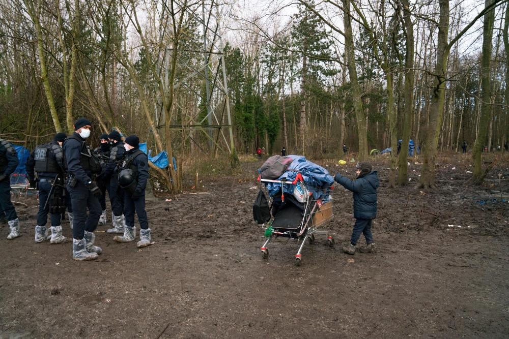 A child stands next to a shopping cart and a group of policemen 