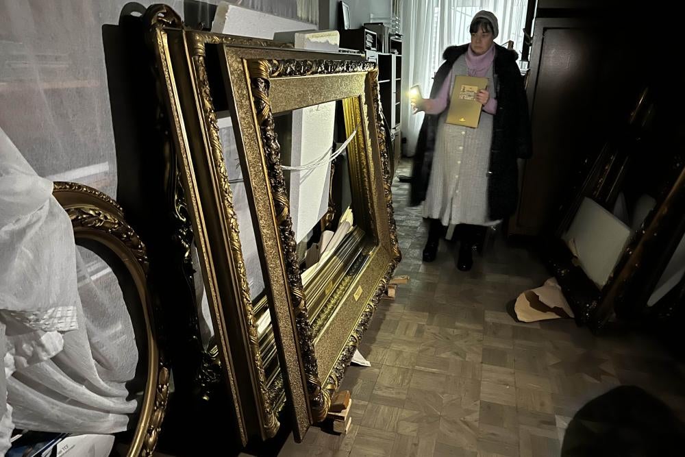A woman shines a flashlight on a stack of empty picture frames