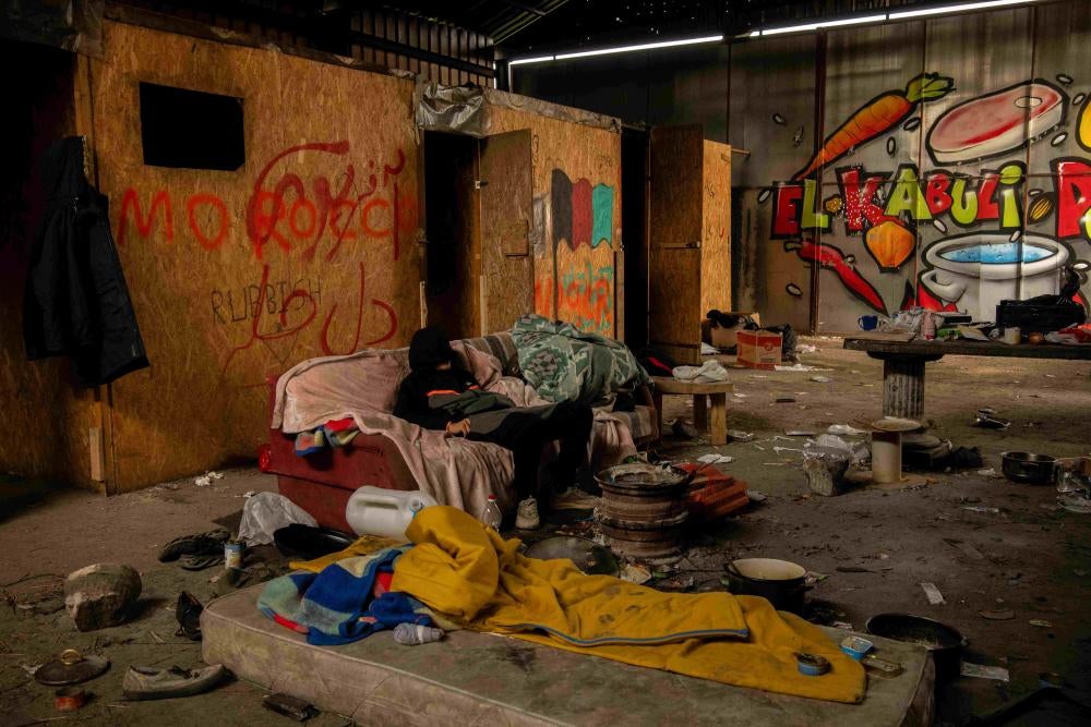 A boy sits on a couch in a squat 