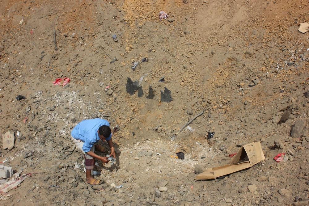 A man collects remnants and debris from one of the impact craters created by the March 15 bombing in Mastaba, northern Yemen. 