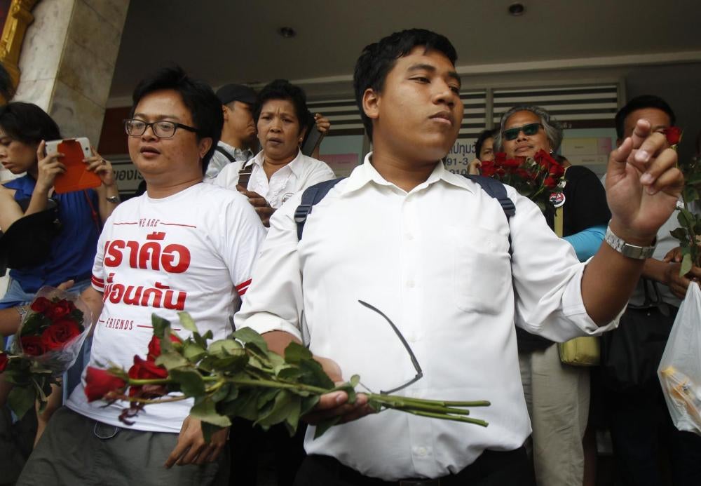 Trois activistes pro-démocratie thaïlandais – l'avocat Anon Numpa (à gauche), l'étudiant Pansak Srithep (à droite), et Sirawit Seritiwat (en arrière-plan à droite, portant des lunettes noires) – quittent un poste de police avant d’être emmenés au tribunal