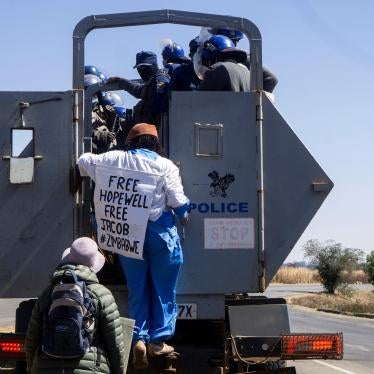 Zimbabwean novelist Tsitsi Dangarembga (center) and her colleague Julie Barnes hold placards as they are arrested during an anti-corruption protest march in Harare, Zimbabwe, on July 31, 2020.  © 2020 ZINYANGE AUNTONY / AFP