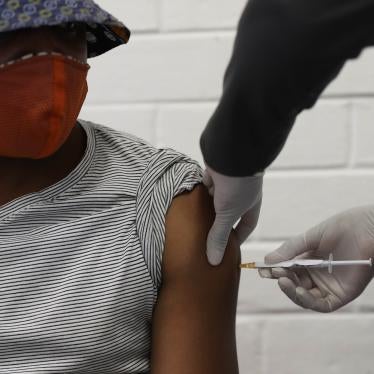 A man wearing a mask receives a vaccination in the arm