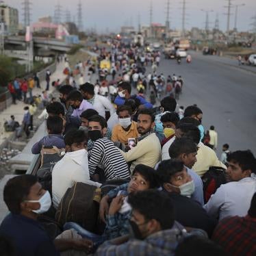 Indian migrant workers sit atop a bus as others walk along an expressway to return to their home villages during a nationwide Covid-19 lockdown, New Delhi, India, March 28, 2020.