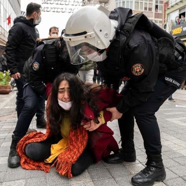 Police forcefully detain a protester  who is crying on the ground while the police stand over her at a demonstration. 