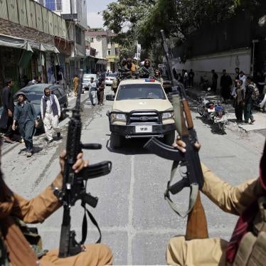Two men hold guns while riding in the back of a truck through a city street