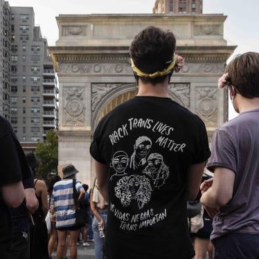 A person wearing a shirt that says "Black Trans Lives Matter (Las vidas negras trans importan)" at a rally