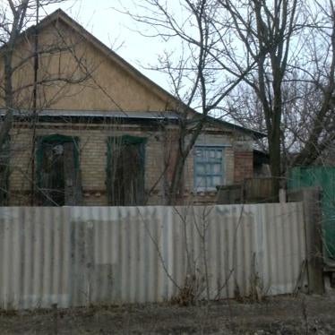 Older woman seating in font of a house in Ukraine