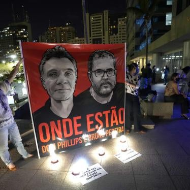 People display a large poster with images of Dom Phillips and Bruno Pereira