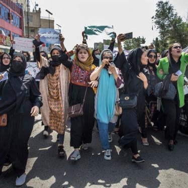 Women march and chant, holding signs during a protest