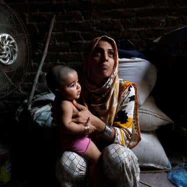 A mother and child sit in front of a fan