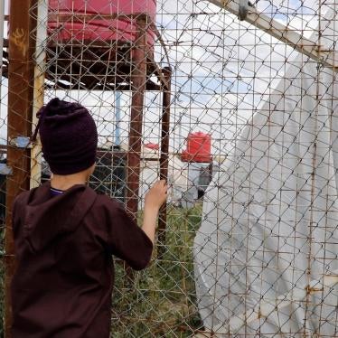 A boy stares through a fence
