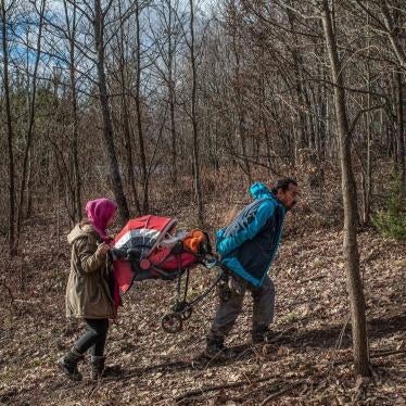 A man and his daughter carry a baby in a stroller through a forest