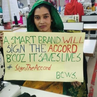 A garment factory worker in Bangladesh holds a sign to stand up for safe factories and the International Health and Safety Accord
