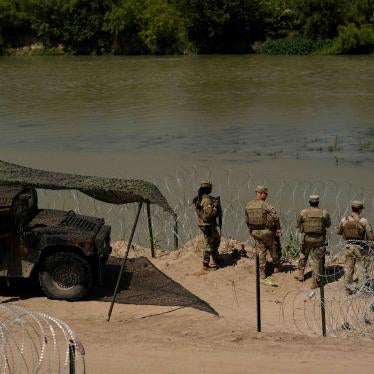 Guardsmen stand by a river lined with razorwire
