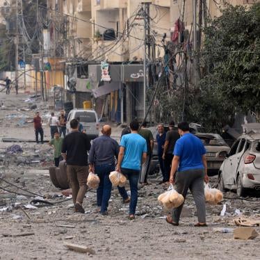  Palestinian men carry bread through a heavily bombed street following Israeli airstrikes on Gaza City on October 10, 2023.  