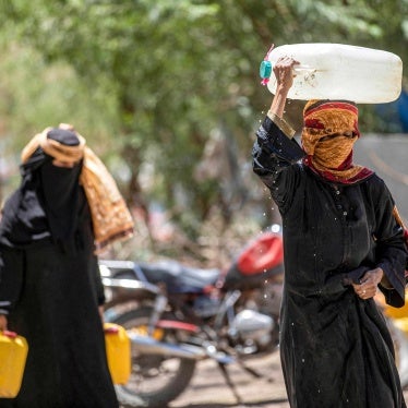 Women walk with canisters filled with water from a tanker truck on the outskirts of Taizz.