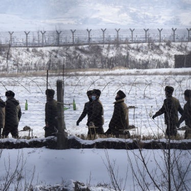 Uniformed border guards patrol next to a fence