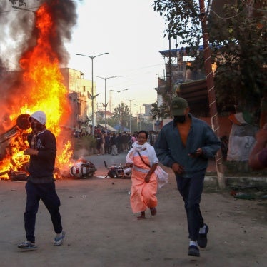 People run past burning vehicles of India's Bharatiya Janata Party (BJP) during a protest to condemn the alleged killing of women and children in Imphal, capital of India's northeastern state of Manipur, November 16, 2024.