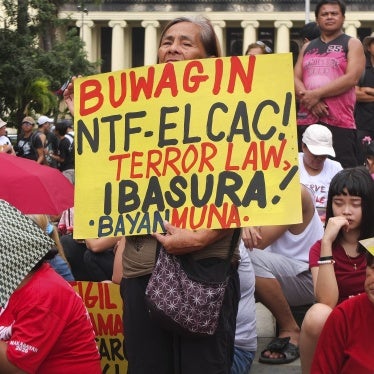 An activist holds a poster calling for abolishing the anti-communist task force