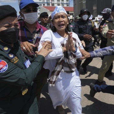Environmental activist Phuon Keoraksmey is escorted by police officers