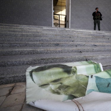 A picture of former Syrian President Bashar Assad lies on the ground as a Syrian opposition fighter stands nearby, inside the Presidential Palace in Damascus, December 8, 2024.