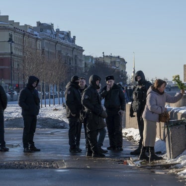 Police watch a woman as she lays flowers at a memorial 